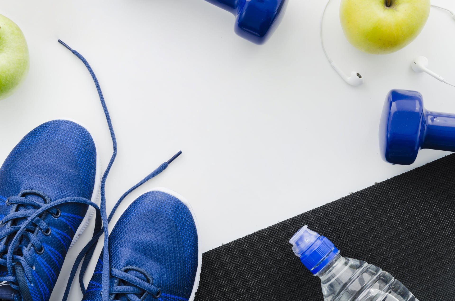 Équipement sportif santé : baskets bleues, haltères, bouteille d’eau, pomme et écouteurs sur un tapis de sport, symbolisant une routine équilibrée